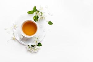 Spring image. Top view cup of green tea on figured saucer with white apple tree flowers on white. photo