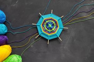 Handmade mandala and multicolored threads on dark grey background. photo