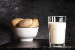 Potato milk glass and bowl with potato tubers on old rusty metal table on black background. photo