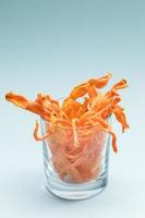 Transparent glass with homemade carrot chips on gentle blue background. photo