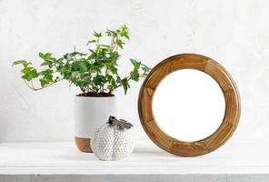 Minimal Halloween or thanksgiving mock up with round wooden frame, houseplant ivy, ceramic pumpkin. photo