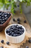 Wild blueberries in white bowl on burlap on wooden table. Natural superfood with vitamins. photo