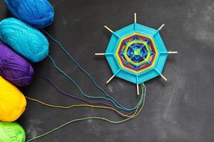 Handmade mandala of multicolor yarn threads on dark grey background. photo