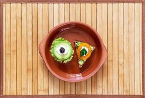 dos sándwiches vegetarianos en un plato de arcilla en el centro de una servilleta de bambú. foto