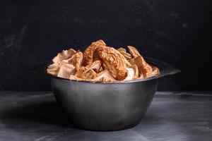 Metal bowl with dried apple slices is standing on dark background. photo