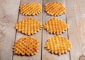 Six fresh baked round waffles laid out on rustic wooden table. photo