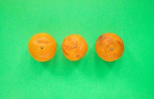 tres feos mandarines no estándar que yacen en medio de un fondo verde. foto