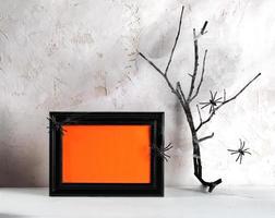 Hallowen minimal image. Black frame with orange empty space for text, spiders, dry twig in cobwebs. photo