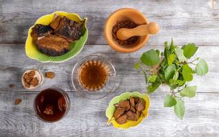 Healing infusion from birch mushroom chaga, ingredients for its cooking and green birch twigs on wooden table. Top view. photo