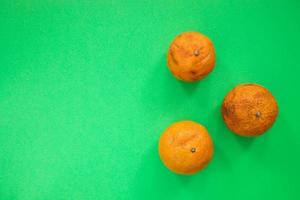 Three ugly non-standard mandarin lying on bright green background. photo