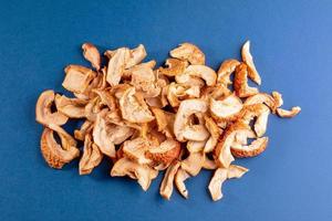 Chaotic bunch of dried apple slices on blue background. photo