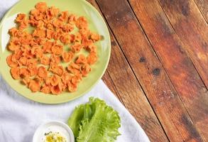 Plate with homemade carrot chips on white napkin on rustic wooden background. photo