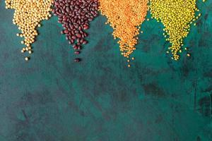 Emerald-green background with scattered in triangular piles on it legumes. photo
