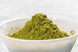 Close-up white bowl full of green japanese matcha tea powder on white background. Antioxidants source for healthy. photo