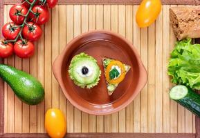 Two vegetarian sandwiches on clay plate and ingredients for cooking on bamboo napkin. photo