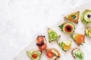 Set of vegetarian sandwiches on parchment paper on white textured background. photo