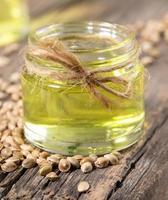 Hemp oil in glass jar and grains of cannabis on background of old wooden boards close-up. photo