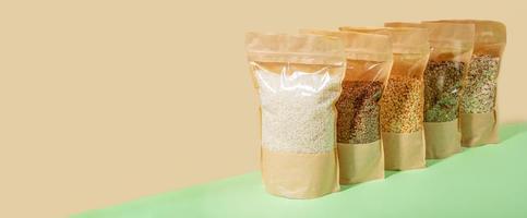 Paper-cellophane bags with cereals standing in diagonal on beige-green. Zero Waste. No plastic. Banner, copy space. photo