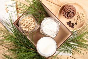 Wooden box with cedar milk glass, jars of flour and nuts, cone, branches on wooden close up. photo