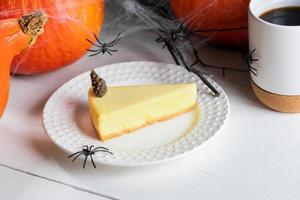Halloween treats - pumpkin pie piece, cup of tea or coffee with pumpkins and black spiders on white. photo