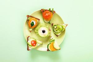 Set of vegetarian sandwiches on round green plate on green background. photo