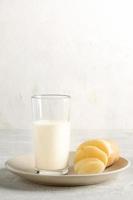 Potato milk in glass with cut potato purified tuber on beige plate on light backdrop. Copy space. photo