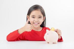 Little Asian girl saving money in a piggy bank, learning about saving, Kid save money for future education. Money, finances, insurance, and people concept photo