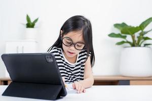 Asian child girl student wow excited on video call learning to studying online class or person learn from home school with tablet photo