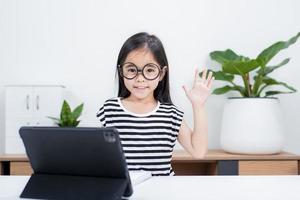 Asian child girl student wow excited on video call learning to studying online class or person learn from home school with tablet photo