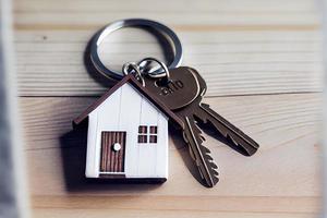 Real estate concept - Key ring and keys on white wooden background photo