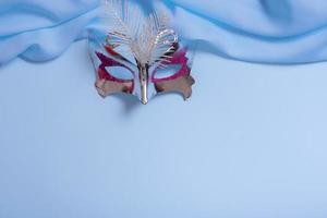 Festive face mask for carnival or masquerade celebration on colored background. Carnival background top view, flat lay