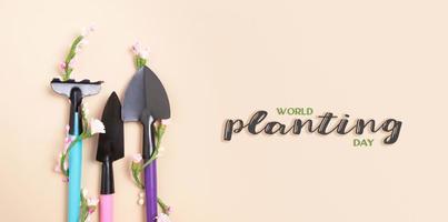 World Planting Day text with shovels and rakes for gardening. flat lay. Banner photo