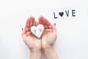 hermosa huella infantil en forma de corazón, las manos de la niña abrazan el corazón. letras de amor foto