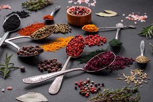 Several types of spices in metal spoons paprika, tomatoes, curry, beets, cumin, turmeric, fennel, spirulina photo