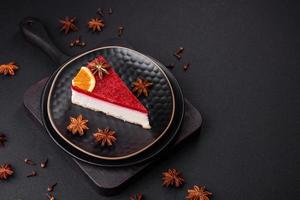 Delicious sweet cheesecake with raspberry jam on a black ceramic plate photo