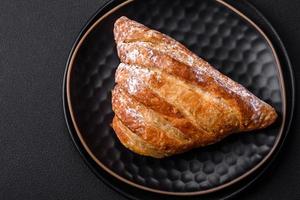 Delicious fresh crispy bun with jam on a black ceramic plate photo