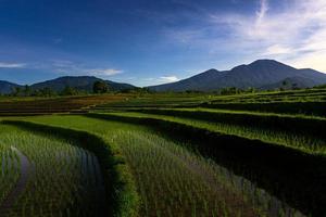 aerial view of indonesian rural area with mountains and rice fields in the morning photo