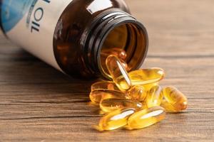 Fish oil Omega 3 capsules vitamin with EPA and DHA isolated on wooden background. photo