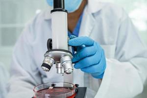 Asian scientist biochemist or microbiologist working research with a microscope in laboratory. For protect outbreak Coronavirus Covid19, bacteria and germs. photo