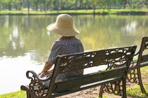 anciana asiática deprimida y triste sentada en un banco en el parque de otoño. foto