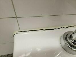 toilet in bathroom with crack in the wall or caulk photo