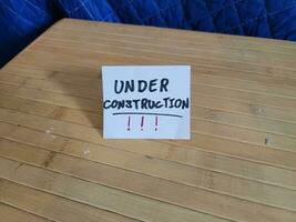 paper under construction sign on brown wood table photo