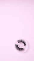 False eyelashes lying on  background. Flatlay, mockup,  top view copy space photo