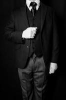 retrato en blanco y negro de mayordomo o sirviente con guantes blancos sobre fondo negro. servicio Industrial. hospitalidad y cortesía profesional foto