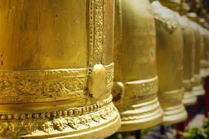 Golden bells hang in a row at Thai Buddhist temples for tourists to use to knock on to make a loud sound to reverberate beliefs to become famous like bells. photo