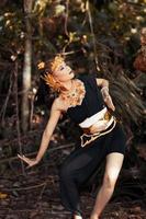 ancient woman in her golden crown and golden necklace pose in her black dress inside the forest photo