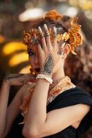 exotic woman in her bold makeup while wearing golden accessories on her head and neck while in a black dress photo