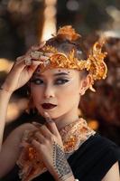 exotic woman in her bold makeup while wearing golden accessories on her head and neck while in a black dress photo