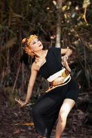 ancient woman in her golden crown and golden necklace pose in her black dress inside the forest photo