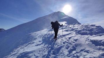 assolo escursionista a piedi nel il montagne su un' molto ventoso soleggiato giorno. all'aperto inverno escursione. inverno in viaggio. avventura e esplorando il montagne. esigente e difficile condizioni per inverno escursionismo. video